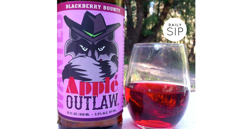 A bottle of apple outlaw with a glass of wine.